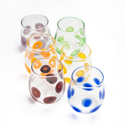 Set of six colorful glass tumblers with dot patterns on a white background